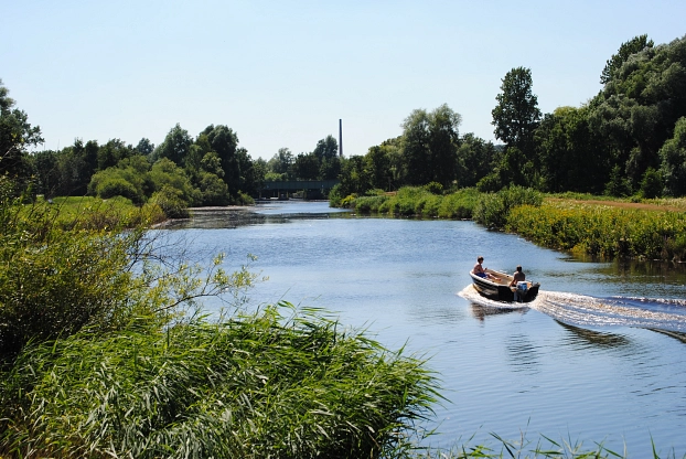 Hamme-Impression Zu sehen ist die Hamme, darauf schwimmend ein schmales Boot mit Motorantrieb, drumherum gibt es viele grüne Pflanzen. © Gemeinde Ritterhude